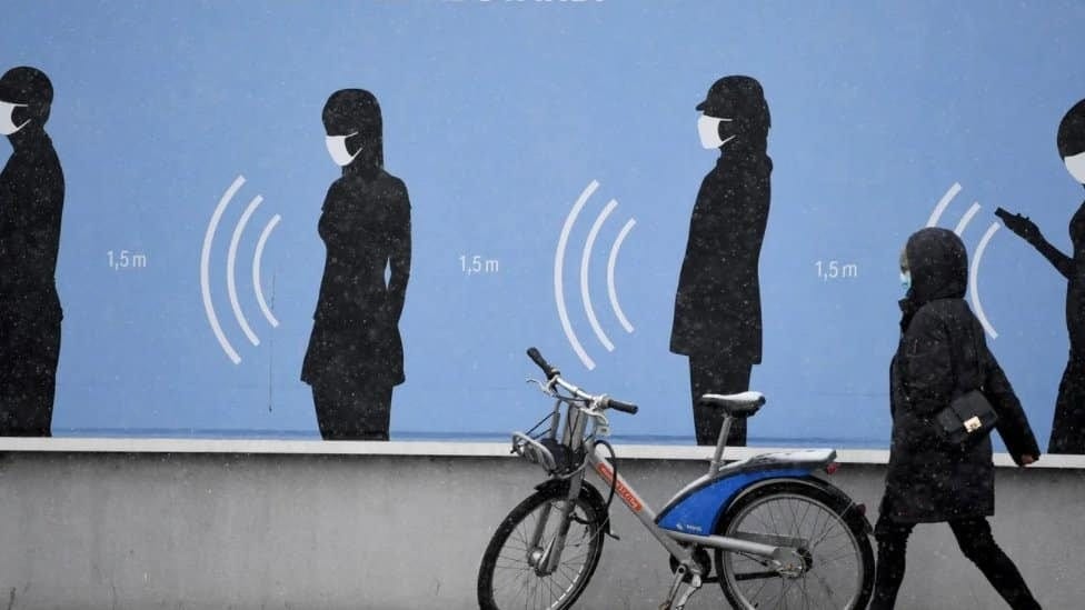 Žena hoda pored plakata u Nemačkoj na kome piše „Najbolji tim. Sa distance