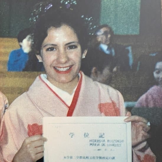 Lourdes holds up her graduation certificate