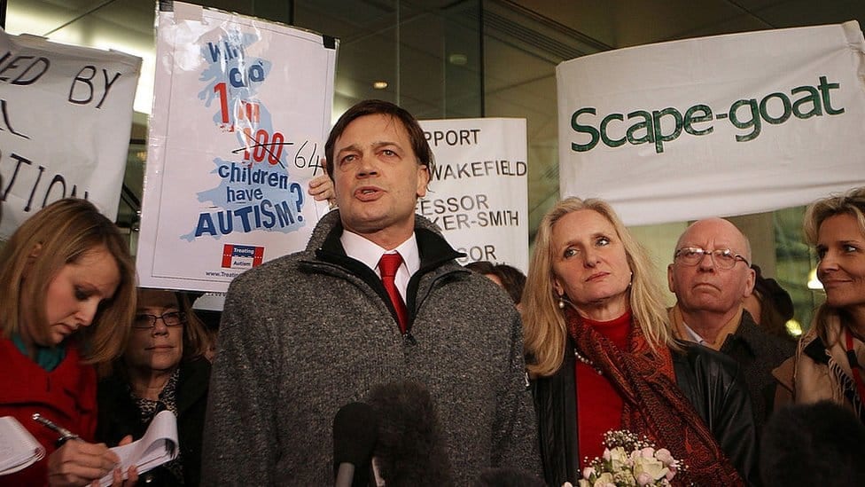 Andrew Wakefield standing with protesters next to a sign saying 