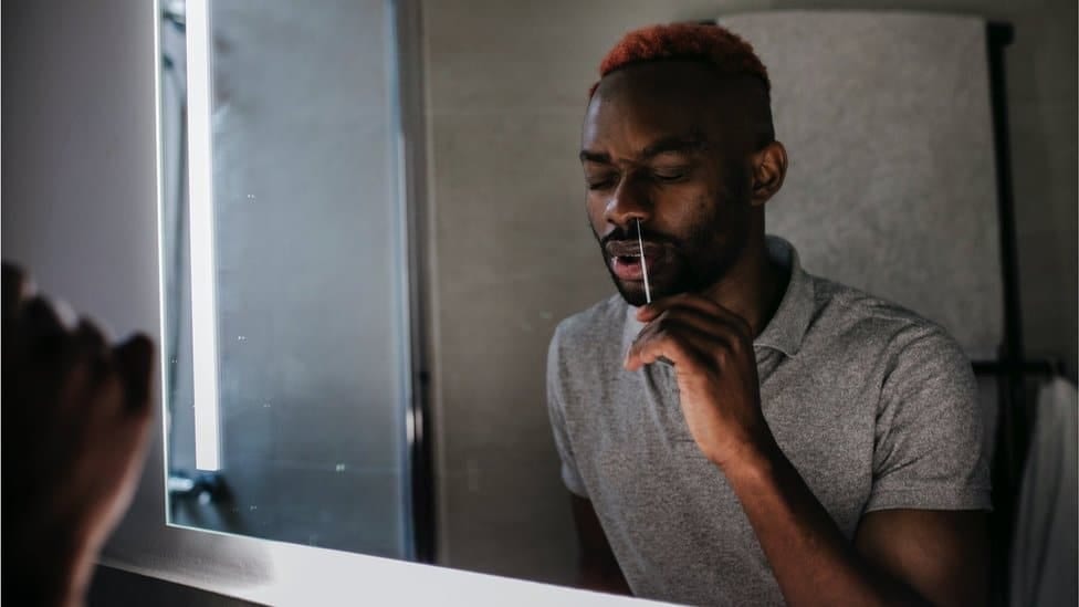 A man swabbing his nose during a lateral flow test at home