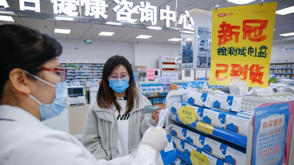 Prodavačica pokazuje komplet za samotestiranje u apoteci u gradu Tjenđinu